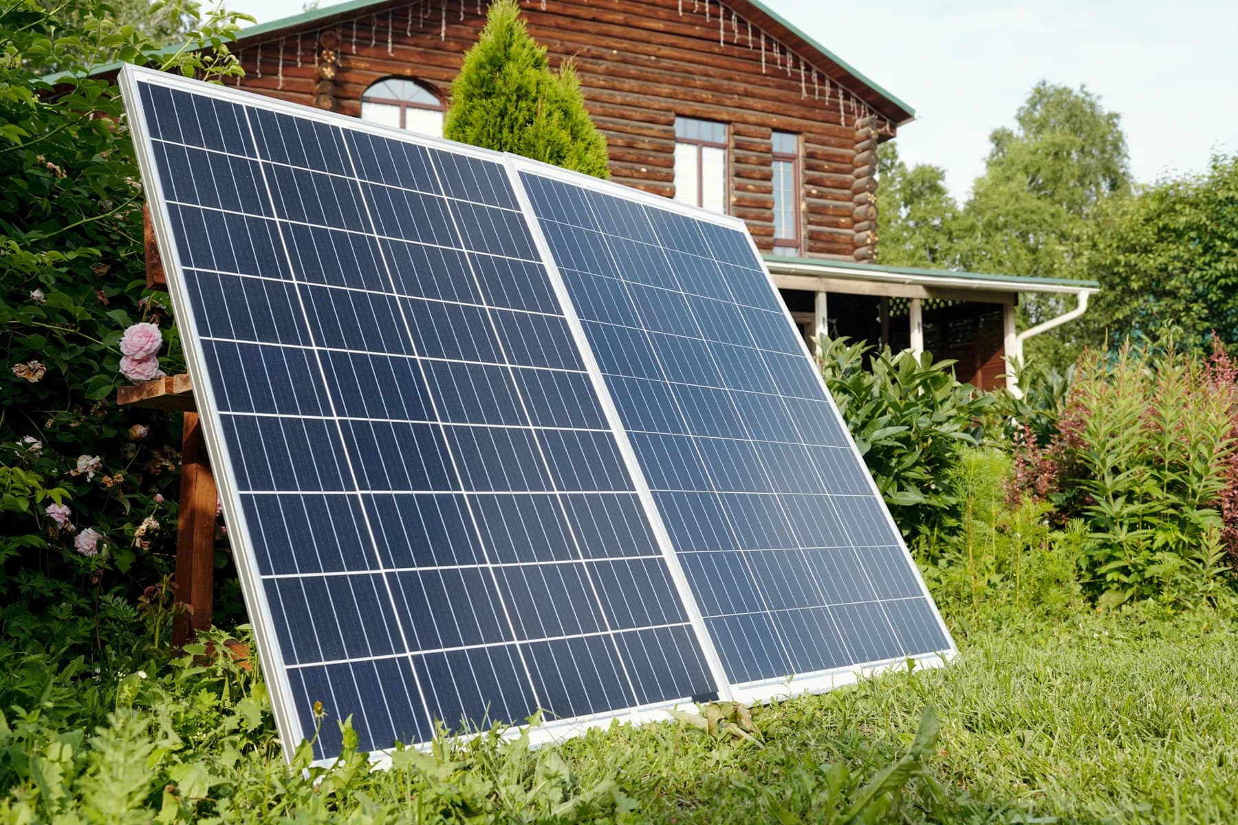 Panneaux solaires au sol devant une maison en bois rond
