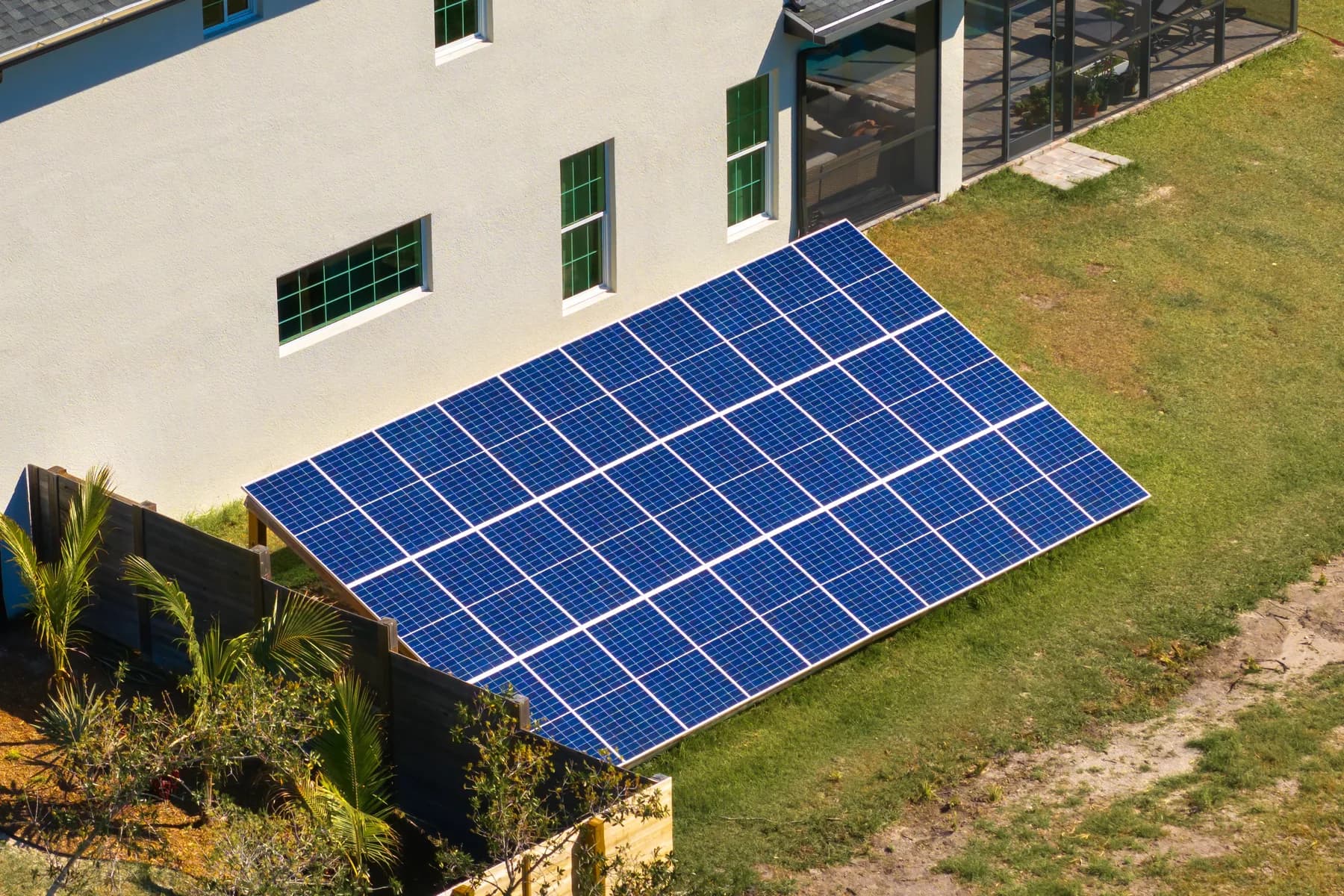 Champ de panneaux solaires au sol installé à côté d’un bâtiment